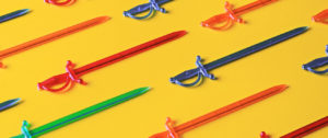 Red, green and blue plastic sword toothpicks on a bright yellow table