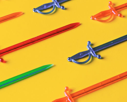 Red, green and blue plastic sword toothpicks on a bright yellow table