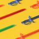 Red, green and blue plastic sword toothpicks on a bright yellow table