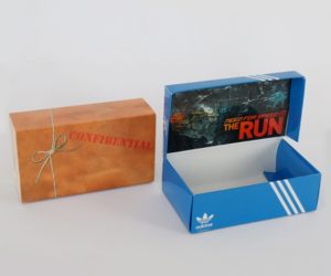 A closed promotional box on the left with the word Confidential on the front and the same box opened to reveal an Adidas promotional shoebox on the right