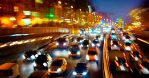 Cars on a highway at night with blurred lights showing fast movement and a downtown area