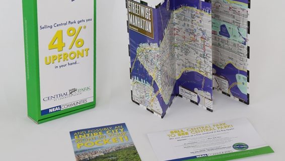 Green and white incentive kit for a real estate company in Manhattan next to a map of the city and brochures