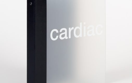 A close up of a light grey binder with a black back binding and the word cardiac across the front