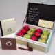 Custom presentation box for teacher appreciation with a chalkboard style writing on the inside of the lid and green and red apples in the box with a card and booklet next to it