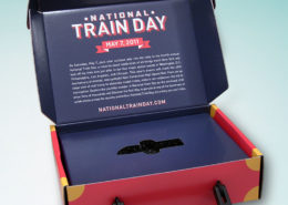 Dark blue 3D mailer for National Train Day with lid open and information on the inside and a custom platform to hold a USB drive