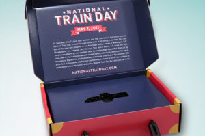 Dark blue 3D mailer for National Train Day with lid open and information on the inside and a custom platform to hold a USB drive