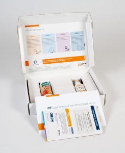 Direct mailer with instructions on the top inside lid, two bottles of medical supplements in protective inserts and a brochure and pamphlet leaning against the box