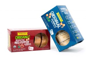 Two organic hummus folding carton boxes for food, one red and another blue box leaning up against it